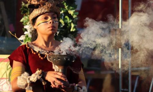 Moscow, Russia - June 2019: Girl as a Mayan Priestess performs an ancient ritual of fire on on Manezh square on Moscow historical festival Times and epochs. Performance by the Mexican group Xipetotek, reenactors of historyof Maya